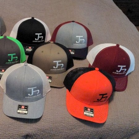 Variety of colorful baseball caps featuring the "J2" logo from Jordan Cash Racing, arranged on a neutral background.